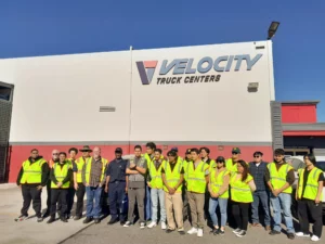 A group of people standing in front of the Velocity Truck centers facility.
