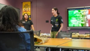 A group of people standing in front of a tv in a classroom during the Wing-EV event.