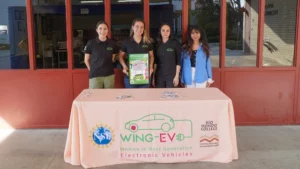 Four women standing in front of a table with Wing-EV signs.