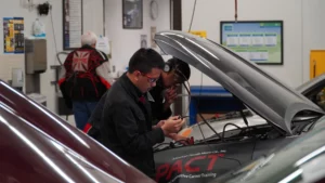 Two technicians working on a car in an automotive repair shop.