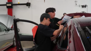 Two individuals inspecting a car at an automotive workshop.