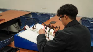 A student working on an electronics project in a classroom setting.