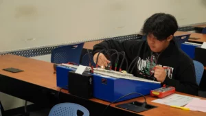 A student working on an electronics project in a classroom setting.