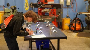 Person measuring components on a workbench in a workshop.
