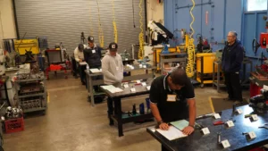 Several individuals working on different tasks in an industrial workshop setting.