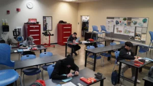 Students working individually at desks in a classroom equipped with technical training equipment.