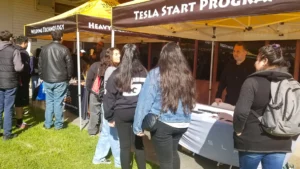 Visitors engaging with representatives at a tesla start program booth during an event.