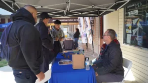 Job fair attendees engage with an exhibitor at an outdoor booth.