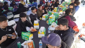 Group of people eating sandwiches at an outdoor event with subway catering.