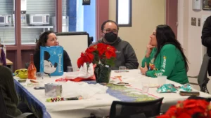 Group of people sitting at a table with festive decorations, engaging in conversation.