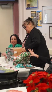 Two women exchanging a gift wrapped in festive paper.