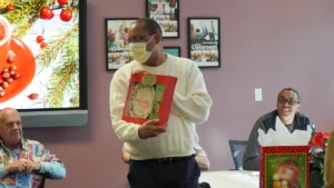 Man holding a christmas gift in an office party setting.