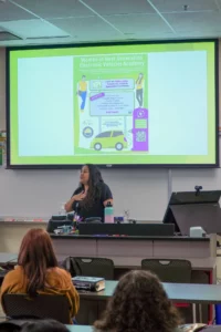 A presenter speaking at a women in next generation electronic vehicles academy event.