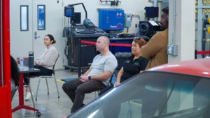 Three adults attentively sitting in a workshop environment during an educational or training session.