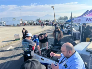 People gathered around a race car at an outdoor racing event.
