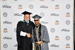 A man shaking hands with another man in graduation gown.